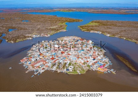 Aerial drone tour over the beautiful island of Mexcaltitan surrounded by water channels of the Laguna Grande with the clear sky and the sunset in the background