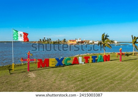 Aerial drone tour of a small island with a restaurant and games for children next to huge colorful letters that say "Mexcaltitan"