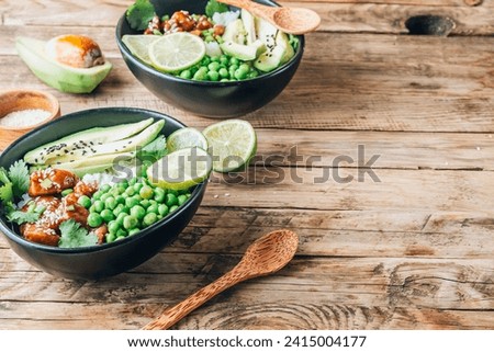 Buddha bowl with crispy sesame chicken asian style. Sweet and sour fried chicken with steamed rice, peas and acocado. Healthy and balanced food concept. Selective focus with copy space Royalty-Free Stock Photo #2415004177