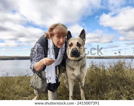Adult girl with shepherd dog taking selfie in forest. Middle aged woman and big shepherd dog on nature. Friendship, love, fun, hugs Royalty-Free Stock Photo #2415007391