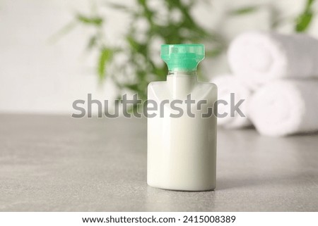 Mini bottle of cosmetic product on light grey table against blurred background, closeup. Space for text