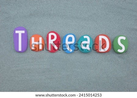 Threads, english word meaning discussions composed with hand painted multi colored stone letters over green sand