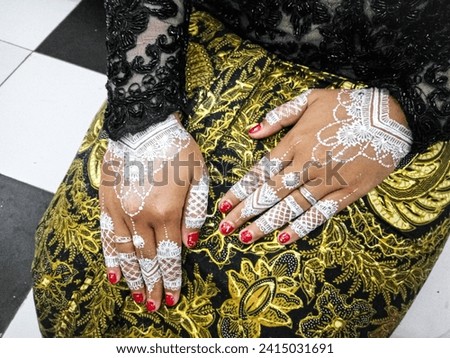 background of art on the hands, henna art with white on both hands and red nail polish