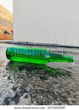 an old glass bottle filled with water flowing out against the background of a wall, picture taken from the side 