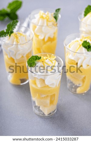 Lemon meringue parfaits in small cups with pound cake and whipped cream