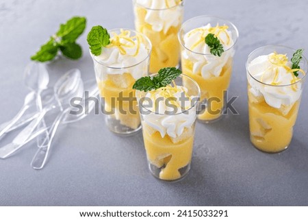 Lemon meringue parfaits in small cups with pound cake and whipped cream