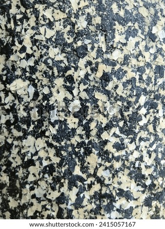 A close-up of the texture of a concrete pillar covered in coloured flakes