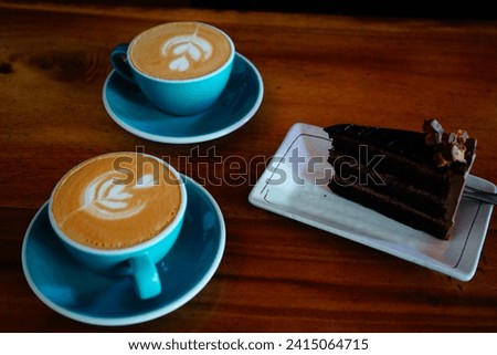 Top view of 2 cups of cappuccino and coffee latte and chocolate brownies cake on wooden table