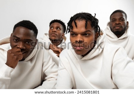 Group of African American guys in brown hoodies posing on a white background