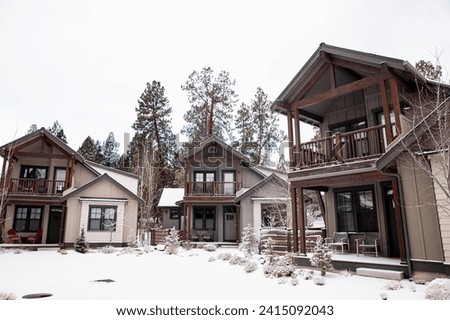 A cluster of modern two story houses in Bend, Oregon in winter. A community of wooden houses with nice landscaping, covered in snow. Snowy winter in a neighborhood. Houses covered in snow in a winter Royalty-Free Stock Photo #2415092043