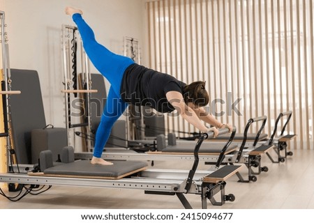 Overweight caucasian woman doing pilates exercises on a reformer. 