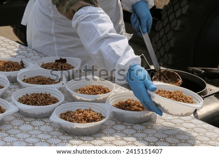 the cook puts buckwheat on plates porridge with stewed meat for the military