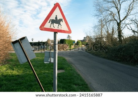 Shallow focus of a worn Horse Riding sign seen in a rural location near a dangerous bend.