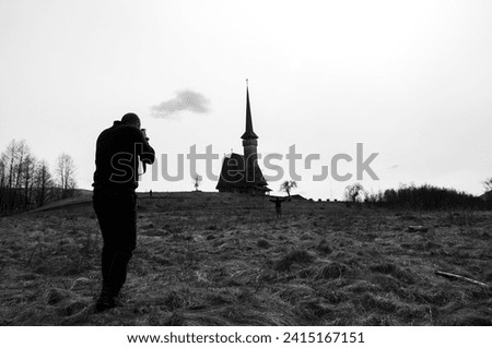 photographer with camera taking picture of a church in maramures, romania, landscape image
