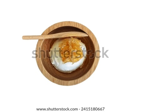 The white background in the picture is a brown wooden cup with white ice cream and a golden-yellow honey cube. A brown wooden spoon is placed 