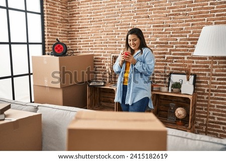 Young beautiful plus size woman smiling confident drinking coffee at new home