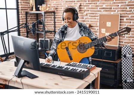African american woman musician composing song playing classical guitar at music studio Royalty-Free Stock Photo #2415190011
