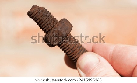 old rusty bolt, iron rod with screw threads, in hand. Rusted mechanical components. holding threaded bolt and nut. dismantling concept, difficult to unscrew, non-removable. isolated on light, close-up Royalty-Free Stock Photo #2415195365
