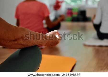 In this sunlit space, a senior woman's hand gracefully engages in various yoga poses, embodying the essence of active aging, health, and inner peace Royalty-Free Stock Photo #2415198889