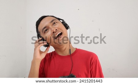happy face of young asian man with headphone listening and enjoying music, podcast, video or radio from smartphone