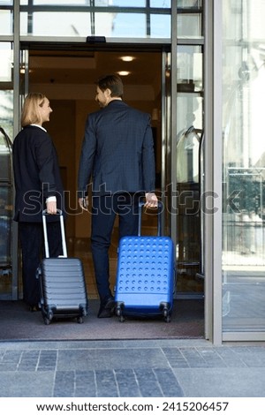 Back view picture of couple with suitcases going inside hotel