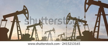 Oil industry equipment silhouette on sunset sky clouds background. Oil pump jack. 