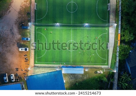 Aerial top view of people playing soccer football sport recreation field ground, national stadium with university or college school campus buildings.Urban city town in Asia. Green court arena at night Royalty-Free Stock Photo #2415214673