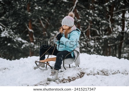 Little girl, happy child sledding down the hill in the snow in winter. Photography, portrait, childhood concept.