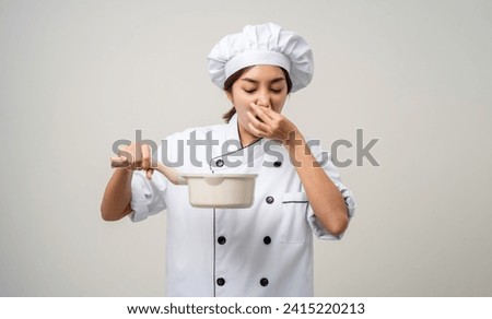 Bad smell and not tasty food. Young asian woman chef in uniform holding soup pot ladle utensils cooking in the kitchen various gesture  on isolated. Cooking woman chef people in kitchen restaurant Royalty-Free Stock Photo #2415220213
