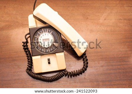 Vintage rotary dial telephone on old wooden table.