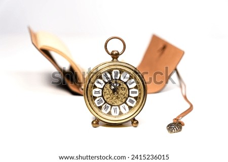 an old golden analog alarm clock with mechanical movement isolated on a white background with notebook