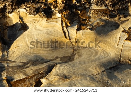 Fine layers of Jurassic sandstones have been eroded on the wave cut platform in the South Bay at Scarborough. The weathering has left an abstract pattern on the rock face. Royalty-Free Stock Photo #2415245711