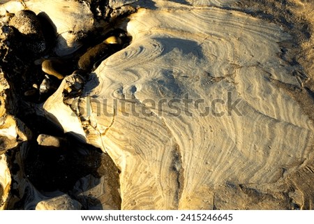 Fine layers of Jurassic sandstones have been eroded on the wave cut platform in the South Bay at Scarborough. The weathering has left an abstract pattern on the rock face. Royalty-Free Stock Photo #2415246645