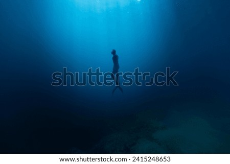 Freediver Swimming in Deep Sea With Sunrays. Young Man DIver Eploring Sea Life. Royalty-Free Stock Photo #2415248653