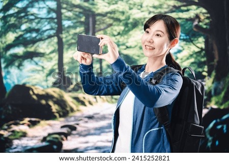 Young woman taking a picture with her phone while hiking