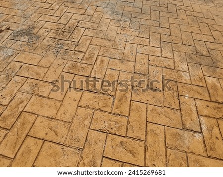 Concrete tiles with geometric shapes, damaged on the exterior pavement of the pedestrian crossing. The colors are shades of brown.