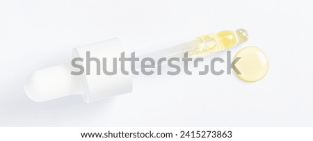 Drops of cosmetic serum and a pipette. A skin care product. White background. Copy space. Royalty-Free Stock Photo #2415273863