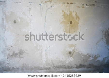 Rough and natural concrete wall with a rough texture. Weathered traces of paintings. Close-up of a building under construction in Marseille, France. Light and natural colors. Grunge texture.