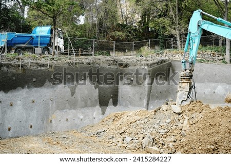 Digger working on construction site against a rain waterd building Foundation - stock photo
Excavation in rock strata for building foundation near Marseille France