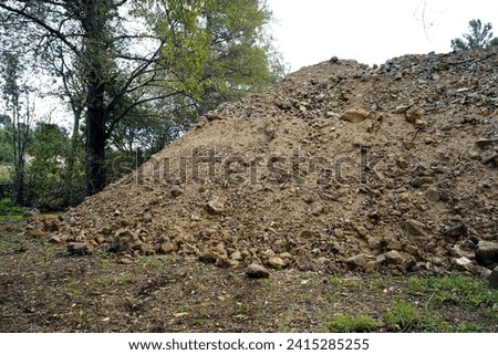 A Pile or heap of earth or dirt from building foundations excavation is stocked on a soccer field - stock photo