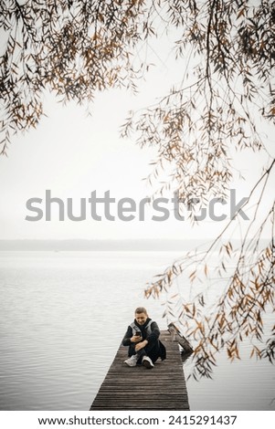 A guy resting on a bridge near an autumn lake