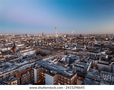 Aerial panoramic shot of apartment houses in Mitte district at twilight. Popular tall Fernsehturm in distance against clear sky. Berlin, Germany