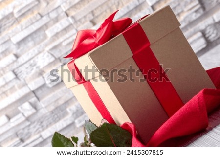Top view,Festive Black Friday surprise, black gift box, adorned with vibrant red ribbon, surrounded by golden star-shaped confetti, set against rich marsala backdrop. Ideal for your Black Friday deals