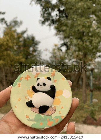 Panda logo on mirror case with background of green trees.
