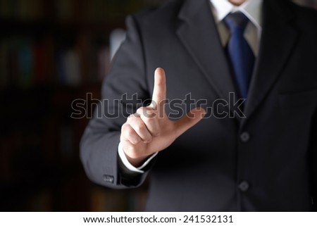 Close-up fragment of a man in a business suit holding a pointing finger in front of him, shallow depth of field composition