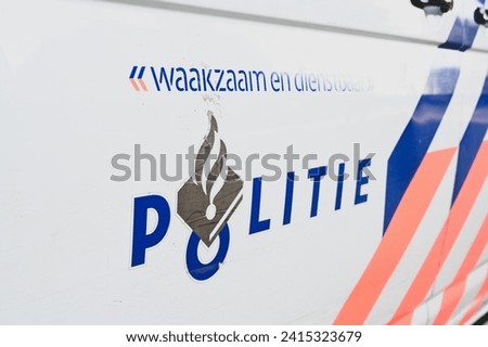Police patrol car on the street in Netherlands. Side view of a police car with the lettering "Police, Watchful and subservient". Police vehicle parked on the street in Holland.