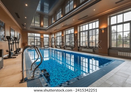 Spacious room with large windows in a private house with a swimming pool. Mirrored ceiling, 
fitness equipment by the pool.