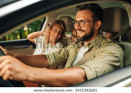 Close shot of father driving a car while the whole family of four is going on a weekend trip away from the city. Parents making a road trip with their daughters in their new car. Transport and safety. Royalty-Free Stock Photo #2415342601