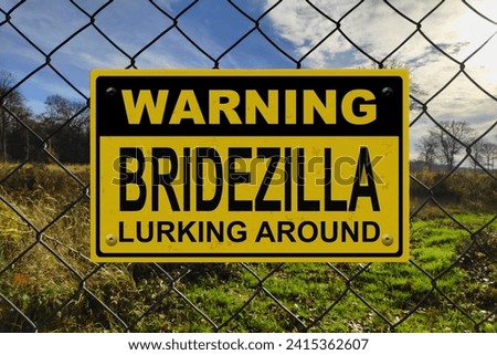 Black and yellow warning sign on a fence with the message "Warning - Bridezilla lurking around".