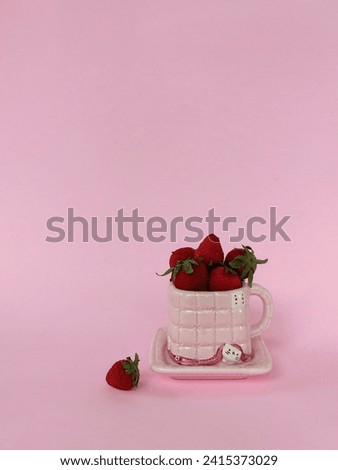A cup of strawberry in pink background. Cute pink cup. Minimalist photography.